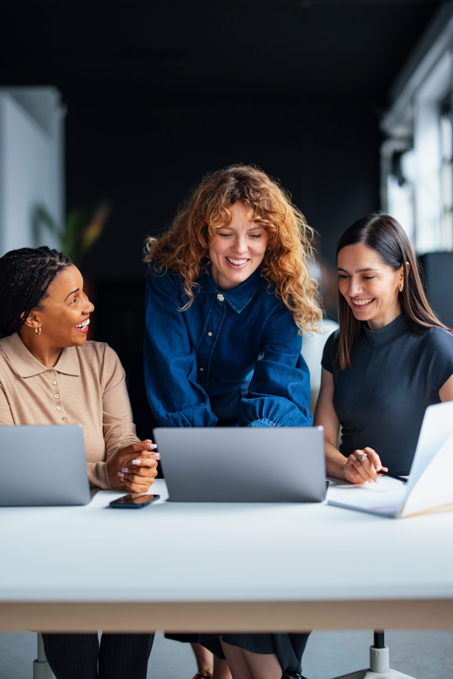 Three women collaborating at office desk.