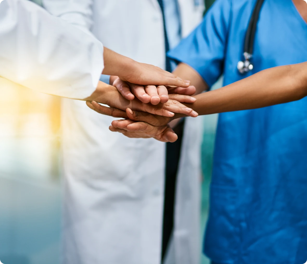 Healthcare team stacking hands together.